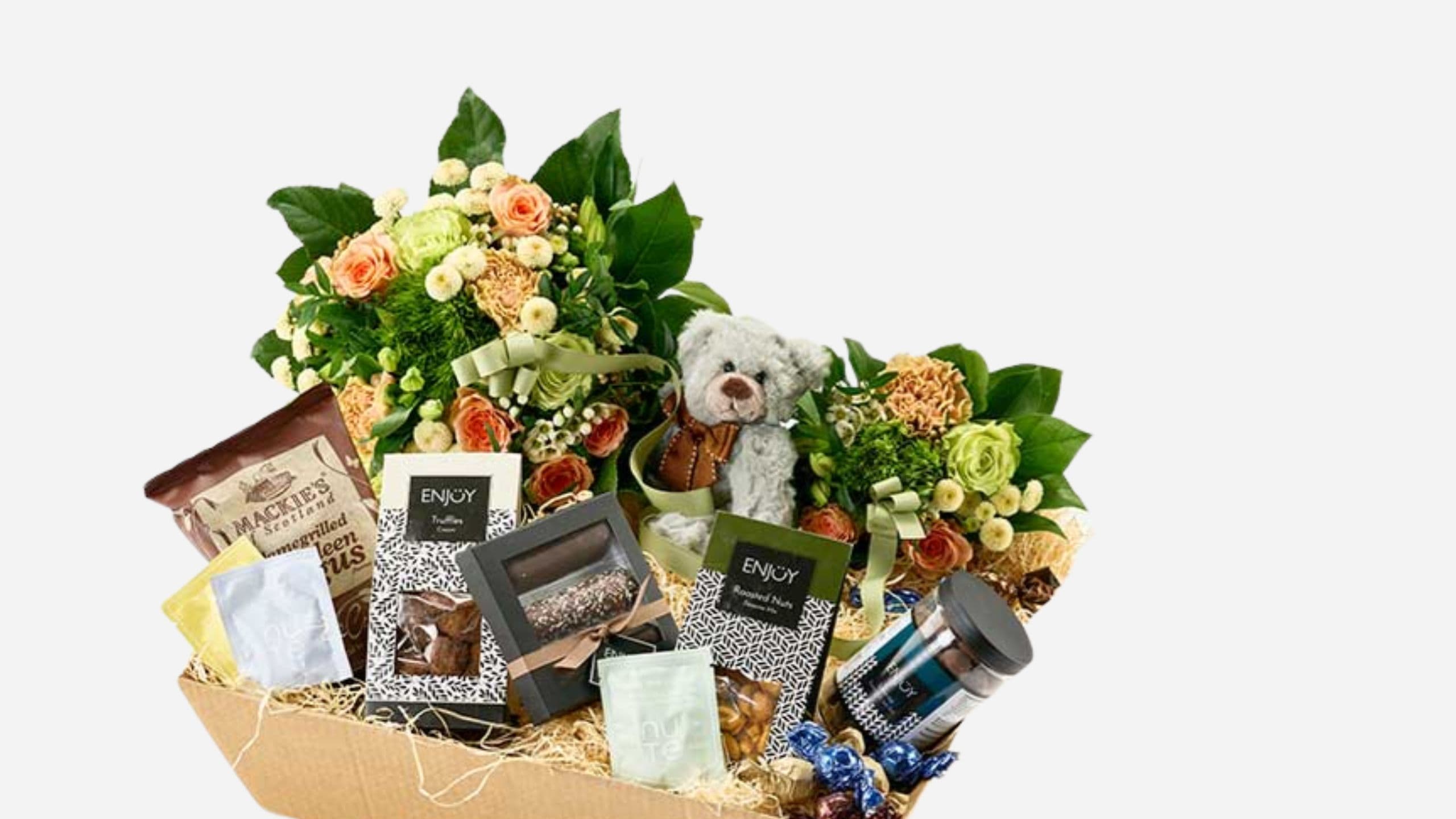 En gavekurv fyldt med to blomsterbuketter, en lille bamse, chokolade, ristede nødder, chips og teposer. Få rabat hos Bloomit.dk