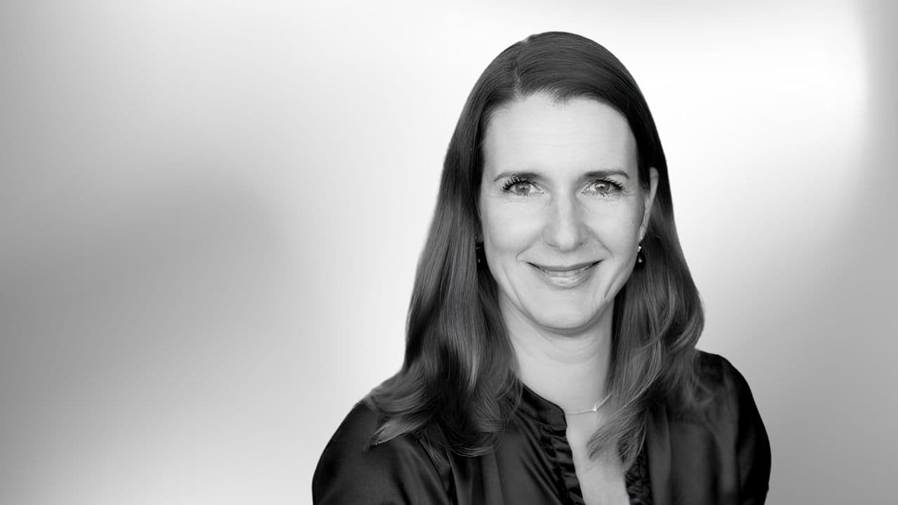 Et portrætbillede af en kvinde, der smiler til kameraet foran en neutral baggrund.